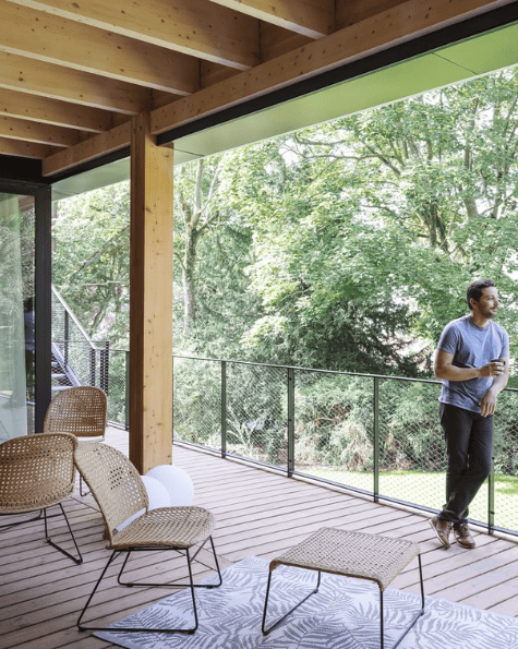 Terrasse en bois lumineuse avec mobilier élégant, vue verdoyante et espace idéal pour une pause détente en extérieur.