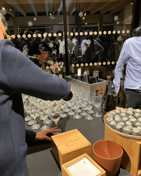 Buffet élégant avec verre de vin et amuse-bouches lors d'un événement convivial dans un espace chaleureux.