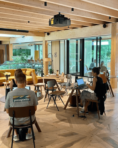 Participants travaillant dans un espace coworking HOWEL lumineux et chaleureux avec vue sur la nature.